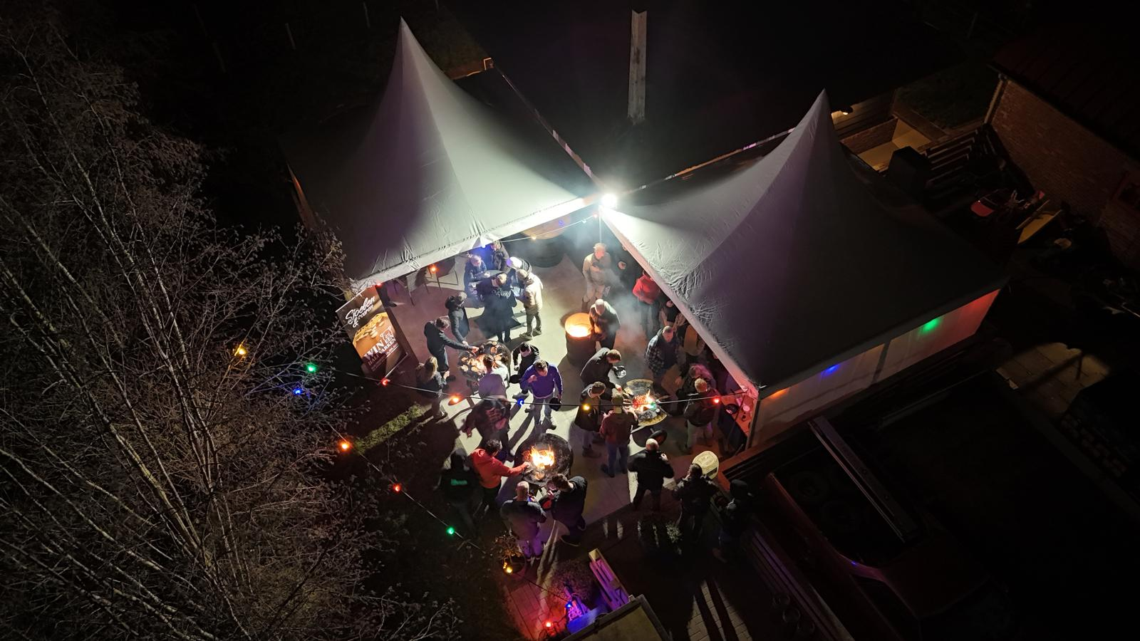 Avondfeest met tenten, vuurschalen en gasten van bovenaf